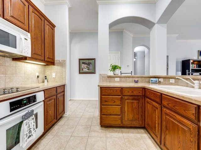 kitchen featuring white appliances, light tile patterned floors, ornamental molding, decorative backsplash, and sink