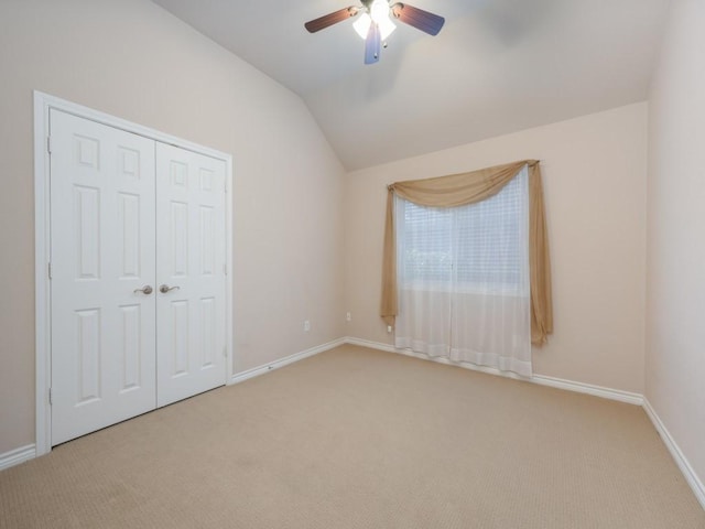 unfurnished bedroom with a closet, ceiling fan, vaulted ceiling, and light colored carpet