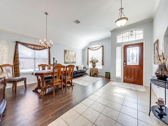 tiled foyer entrance featuring vaulted ceiling, a notable chandelier, crown molding, and a healthy amount of sunlight