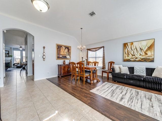 dining space featuring a healthy amount of sunlight, ornamental molding, light tile patterned flooring, and ceiling fan with notable chandelier