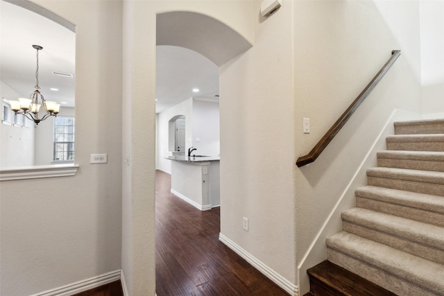 staircase featuring sink, a notable chandelier, and hardwood / wood-style flooring