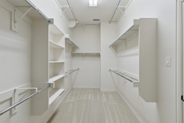 walk in closet with light carpet