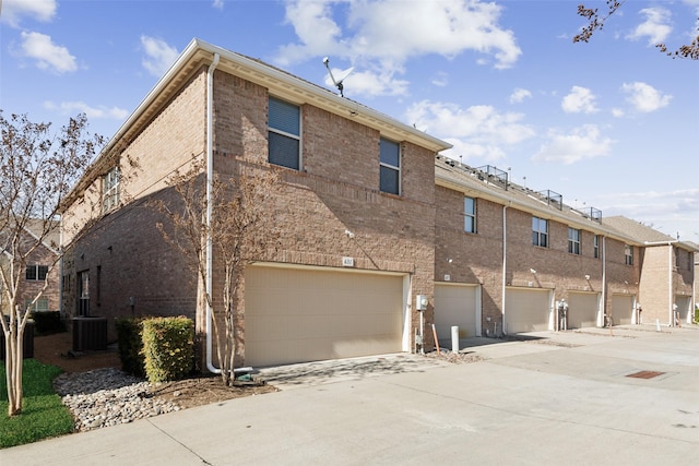 rear view of property featuring a garage and central AC unit