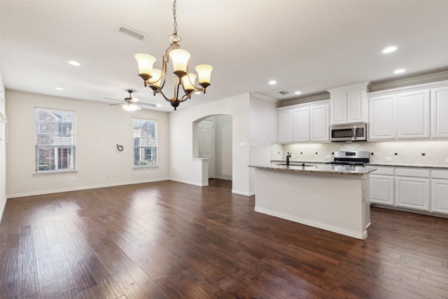 kitchen featuring stainless steel appliances, white cabinets, stone countertops, hanging light fixtures, and dark hardwood / wood-style flooring