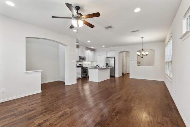 unfurnished living room featuring ceiling fan with notable chandelier, sink, and dark wood-type flooring