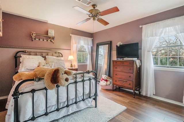 bedroom featuring multiple windows, ceiling fan, and light wood-type flooring