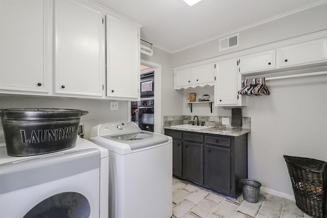 clothes washing area with sink, ornamental molding, washer and dryer, and cabinets