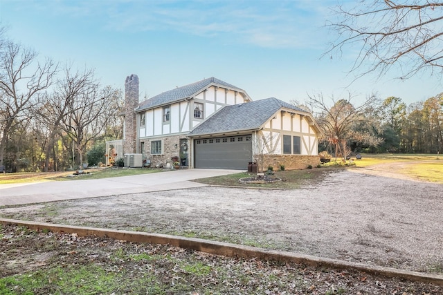 tudor-style house featuring central air condition unit and a garage