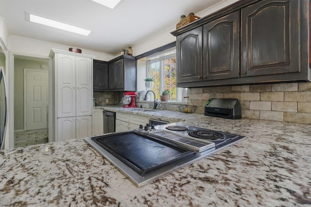 kitchen with sink, black dishwasher, dark brown cabinetry, backsplash, and light stone countertops