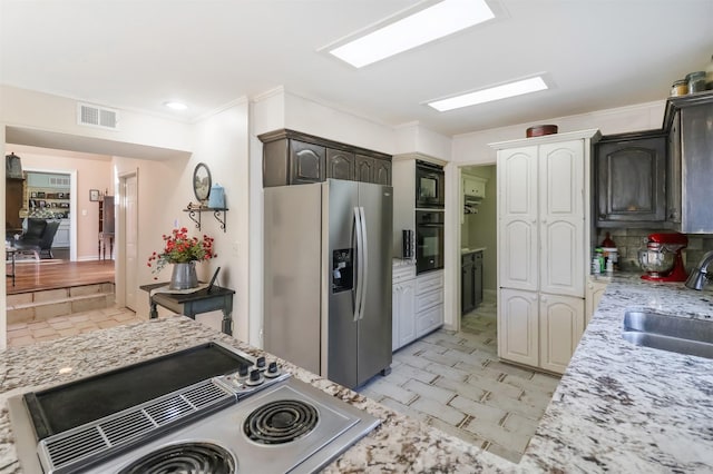 kitchen featuring black appliances, dark brown cabinets, light stone countertops, and sink