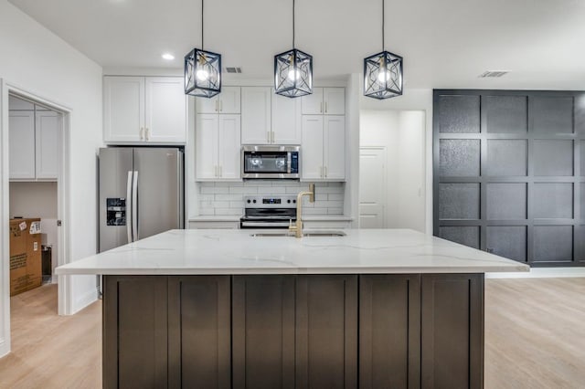 kitchen with sink, white cabinetry, appliances with stainless steel finishes, and an island with sink