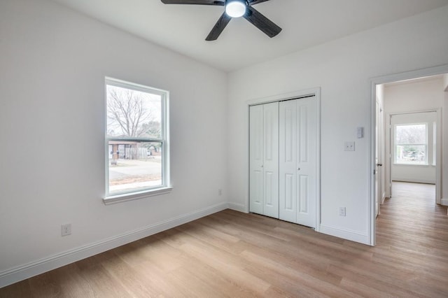 unfurnished bedroom with light wood-type flooring, ceiling fan, and a closet