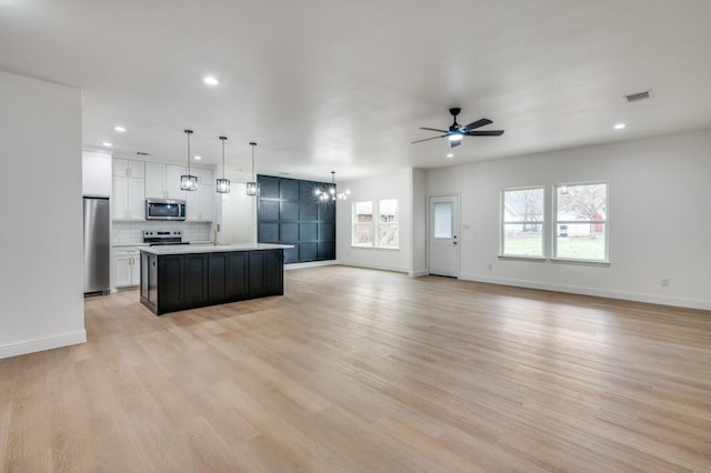 kitchen featuring light hardwood / wood-style flooring, hanging light fixtures, an island with sink, stainless steel appliances, and white cabinets