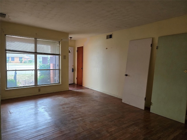 unfurnished room with dark wood-type flooring and a textured ceiling