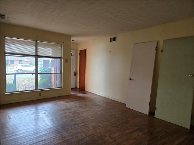 empty room featuring dark hardwood / wood-style floors and a textured ceiling