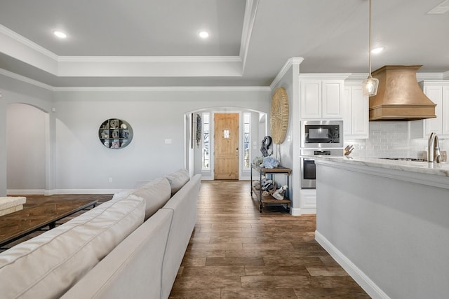 living room with a raised ceiling, crown molding, and dark hardwood / wood-style floors