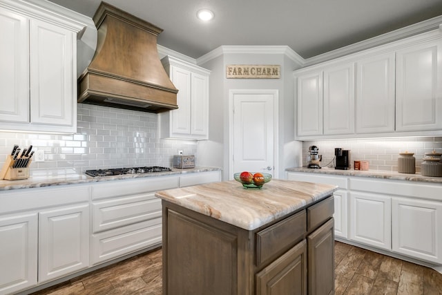 kitchen featuring white cabinetry, stainless steel gas stovetop, backsplash, and premium range hood