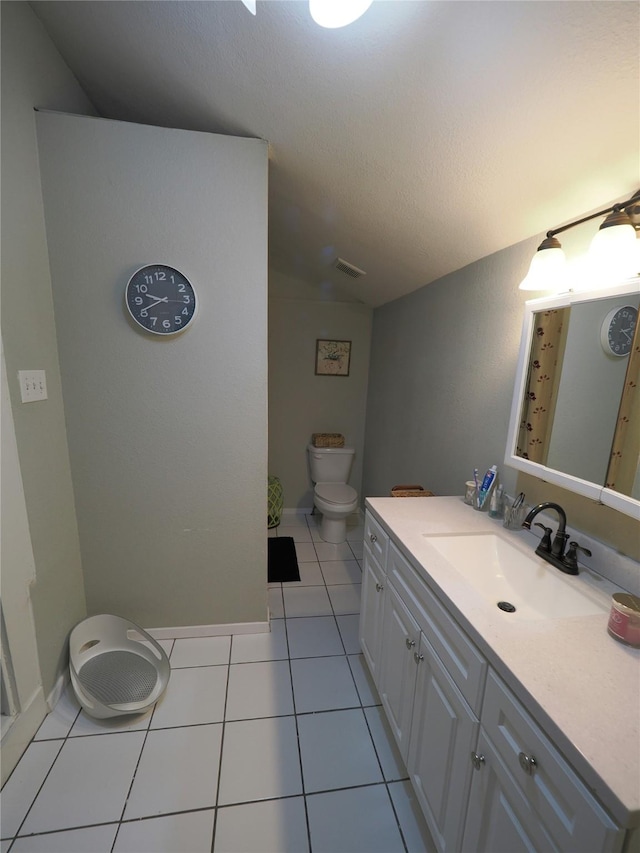 bathroom with a textured ceiling, vaulted ceiling, tile patterned flooring, toilet, and vanity