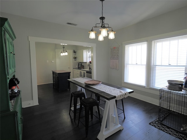 dining area featuring sink, a notable chandelier, and dark hardwood / wood-style floors