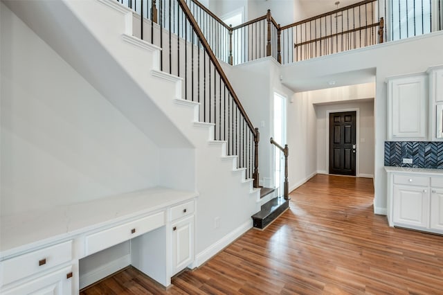 foyer entrance featuring light wood-type flooring, built in desk, and a high ceiling