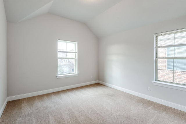 carpeted spare room with vaulted ceiling