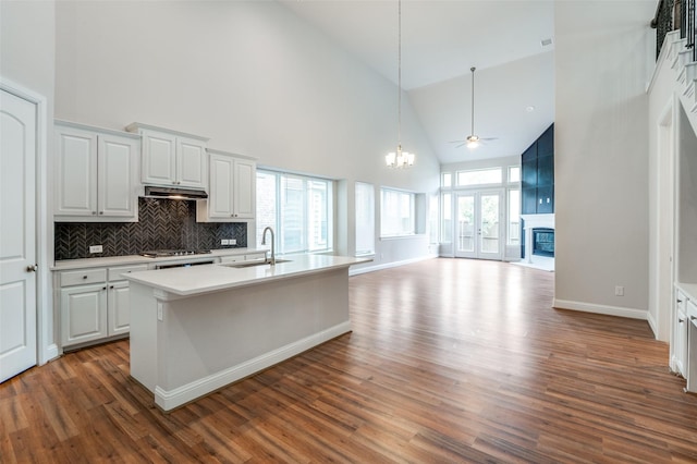 kitchen with white cabinetry, an island with sink, sink, backsplash, and high vaulted ceiling