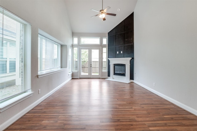 unfurnished living room with high vaulted ceiling, ceiling fan, a large fireplace, and hardwood / wood-style floors