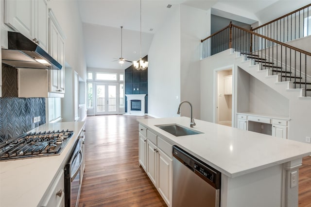 kitchen featuring pendant lighting, white cabinetry, stainless steel appliances, sink, and a kitchen island with sink