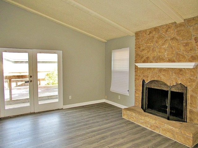 unfurnished living room featuring french doors, a stone fireplace, lofted ceiling with beams, and hardwood / wood-style flooring