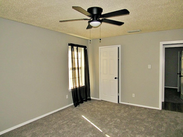 unfurnished bedroom with a textured ceiling, ceiling fan, and dark carpet