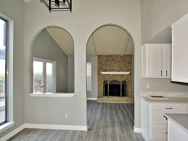 kitchen with white cabinets, light wood-type flooring, a healthy amount of sunlight, and a stone fireplace