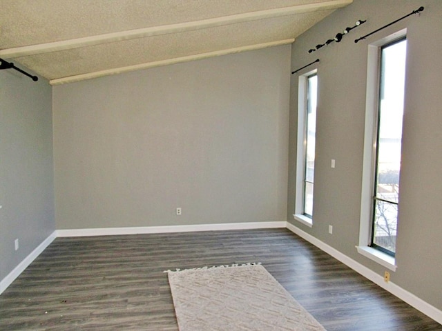 unfurnished room featuring plenty of natural light, lofted ceiling with beams, and dark hardwood / wood-style floors