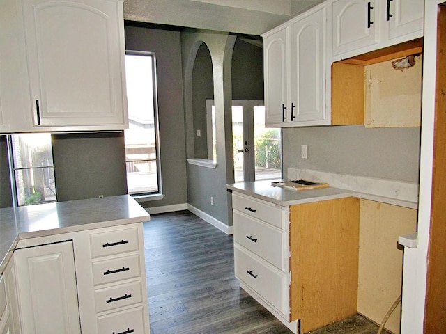 kitchen with kitchen peninsula, white cabinets, dark wood-type flooring, and a healthy amount of sunlight