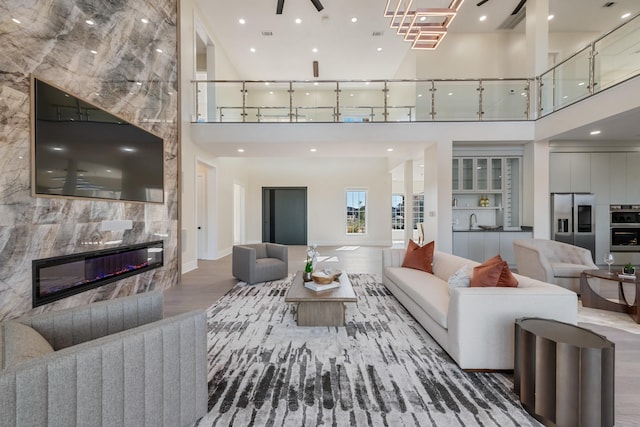 living area with recessed lighting, a high ceiling, wood finished floors, and a tile fireplace