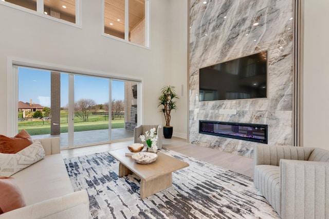 living area with a fireplace, a high ceiling, baseboards, and wood finished floors