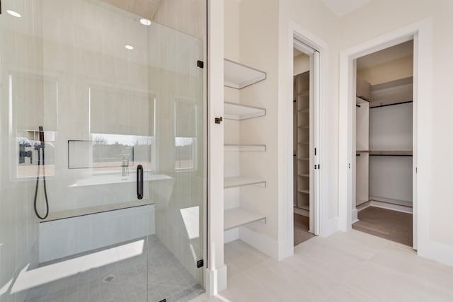 bathroom with a shower with door and tile patterned floors