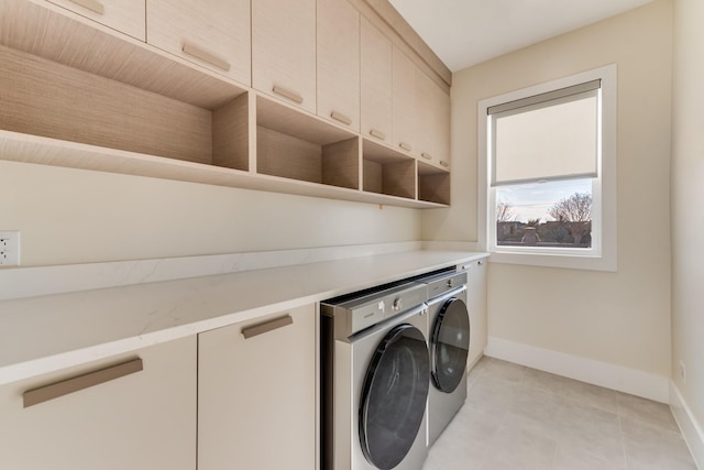 laundry room featuring washing machine and dryer, light tile patterned floors, and cabinets