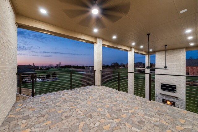 patio terrace at dusk featuring a balcony and a fireplace