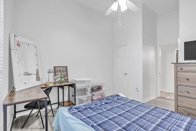 bedroom featuring a towering ceiling, ceiling fan, crown molding, and light hardwood / wood-style floors