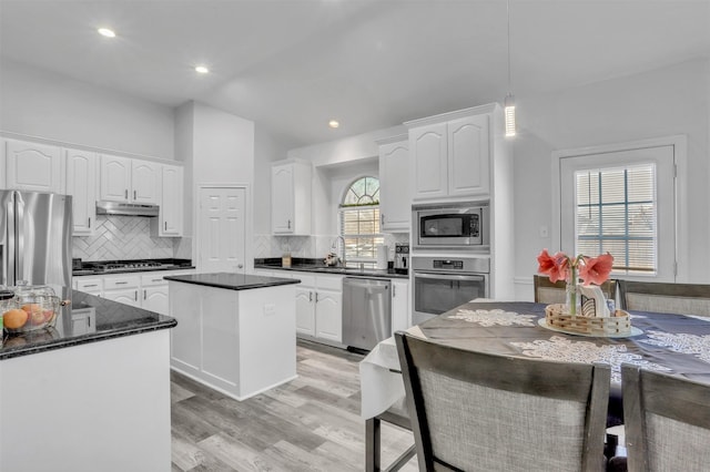 kitchen featuring white cabinets, stainless steel appliances, tasteful backsplash, and a kitchen island