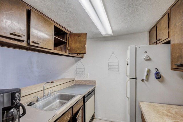 kitchen featuring sink, white fridge, stainless steel dishwasher, and a textured ceiling