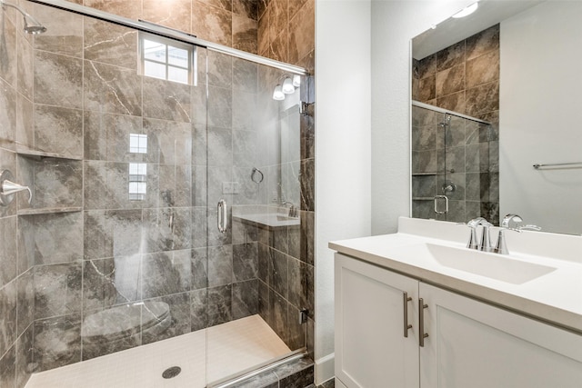 bathroom featuring a shower with door and vanity