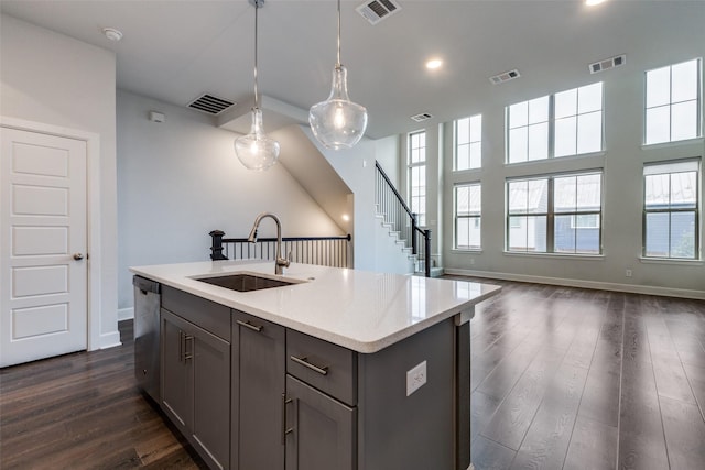 kitchen featuring dark wood-type flooring, dishwasher, hanging light fixtures, a center island with sink, and sink