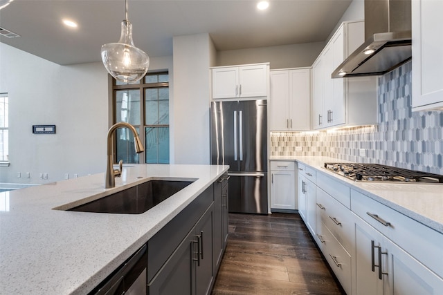 kitchen with stainless steel appliances, white cabinets, wall chimney range hood, and sink