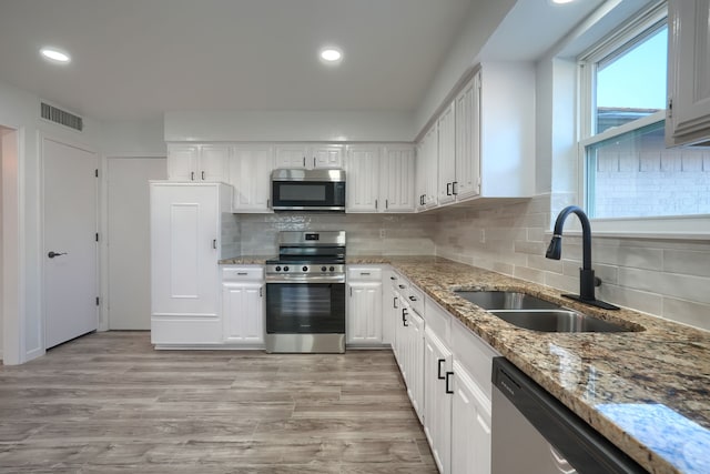 kitchen with visible vents, stainless steel appliances, light wood-style floors, white cabinetry, and a sink