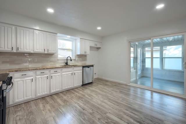 kitchen featuring light wood finished floors, decorative backsplash, appliances with stainless steel finishes, white cabinetry, and a sink