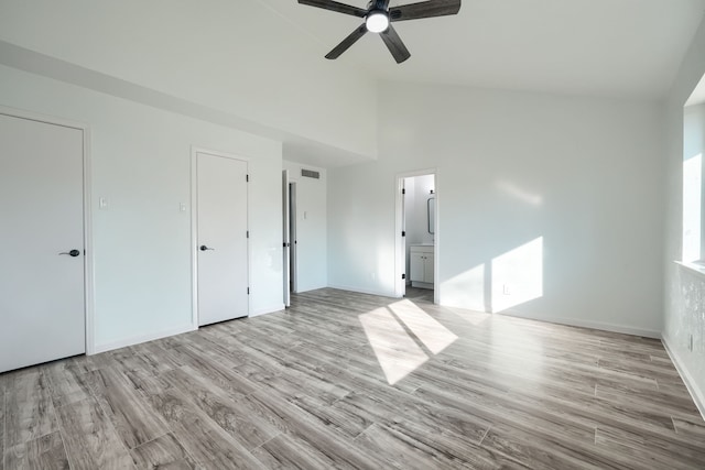 unfurnished bedroom featuring ensuite bathroom, high vaulted ceiling, light wood-style flooring, visible vents, and a ceiling fan