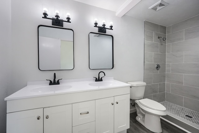 full bathroom with toilet, visible vents, a sink, and tiled shower