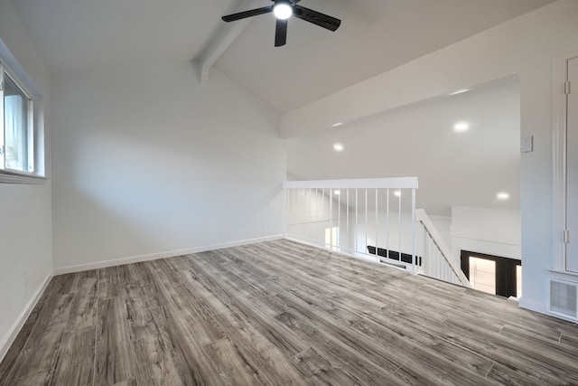 empty room with lofted ceiling with beams, wood finished floors, visible vents, and a healthy amount of sunlight