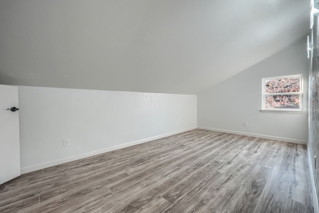 additional living space with vaulted ceiling, wood finished floors, and baseboards